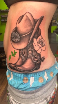 a tattoo of a cowboy hat and boots on a woman's stomach